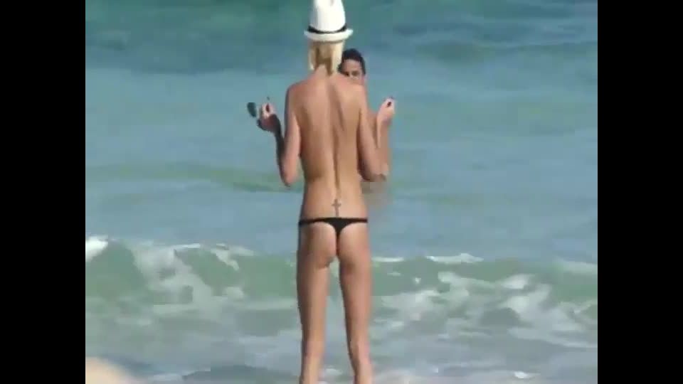 Skinny topless girl enters the water