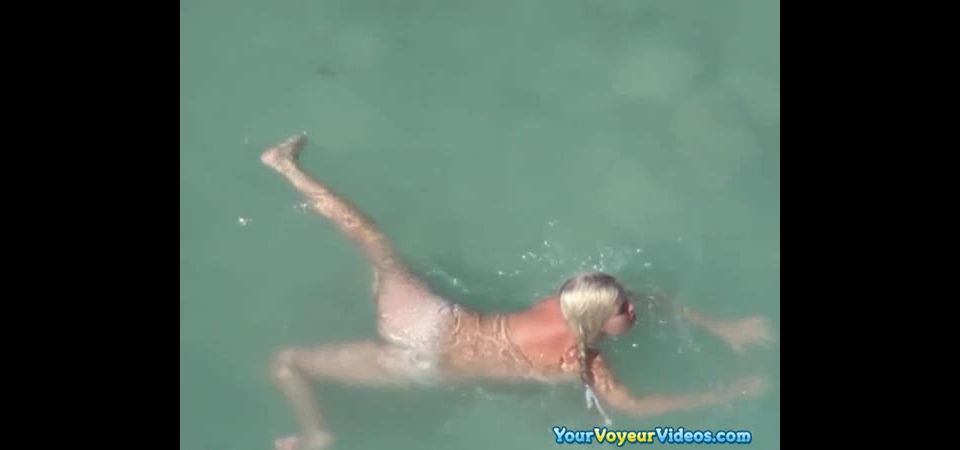 Blonde nudist chick swimming in the water