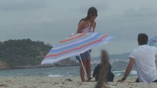 Topless milf gives back rub on beach