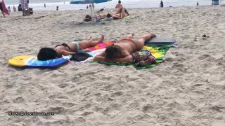 A beach voyeur is approching two nice girls because the bikini bra is so big that nipples are  visible